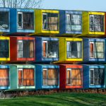 Vibrant exterior of colorful modular housing units with varied window designs.